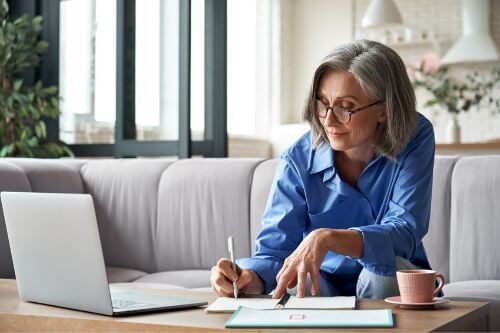A woman signs a real estate contract on her coffee table at home